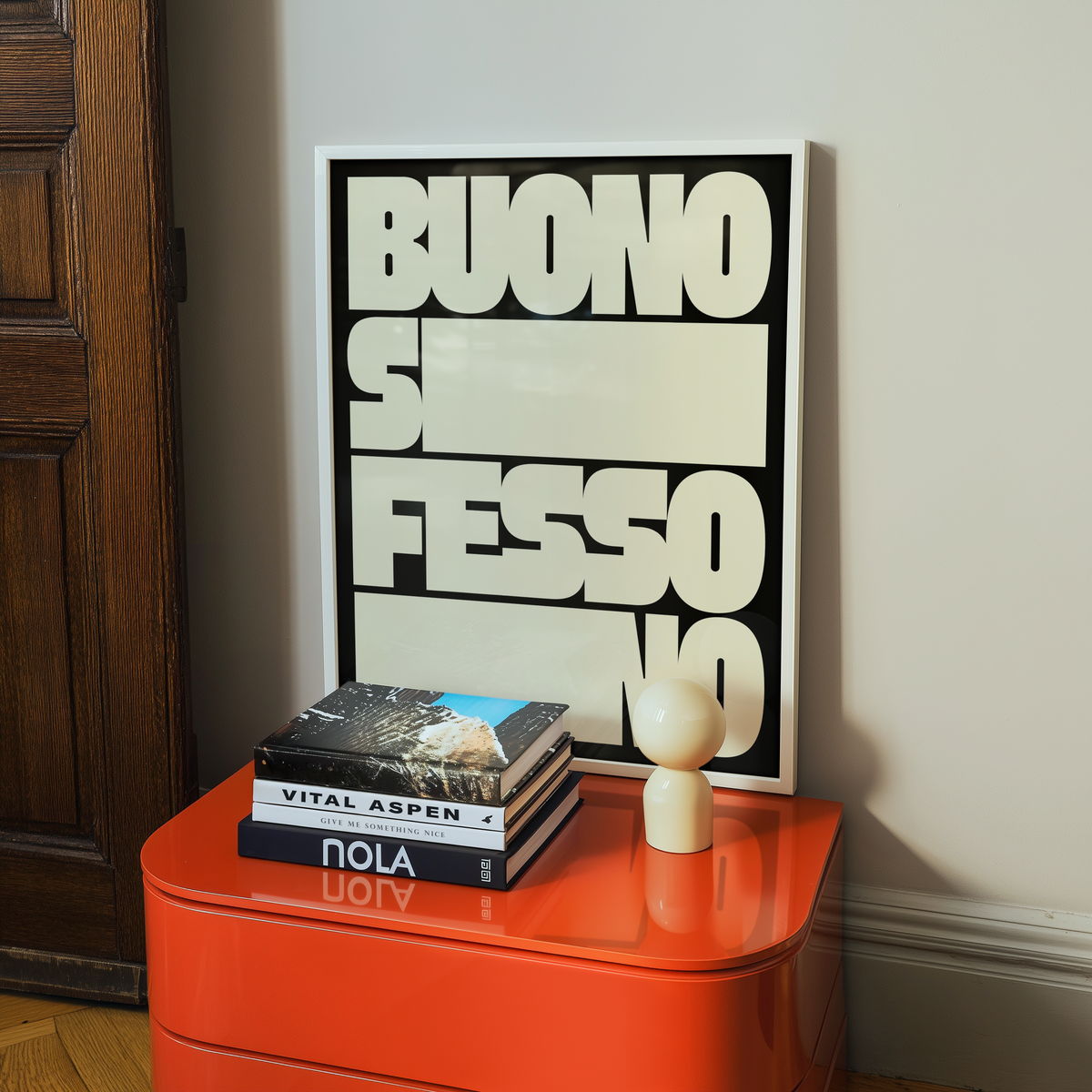 Poster Buono sì, fesso no in cornice bianca su una cassettiera arancione