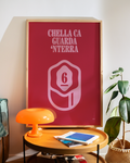 Poster Smorfia 6 «Chella ca guarda 'nterra» in cornice di legno chiaro appoggiato in camera da letto, sopra un tavolino con lampada arancione e pianta